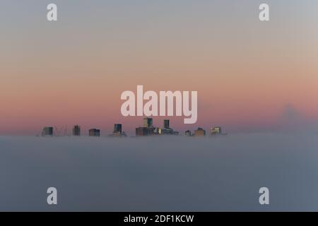 Stadt in den Wolken, Paradise City, City of Angels, Vancouver City Wolkenkratzer über dem Nebel mit der Morgensonne, die einen reflektierenden falschen Sonnenuntergang erzeugen Stockfoto