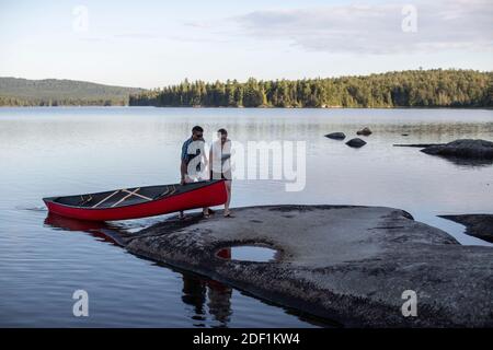 Afrikanischer Mann und weiße Frau ziehen Kanu an Land Teich in Maine Stockfoto