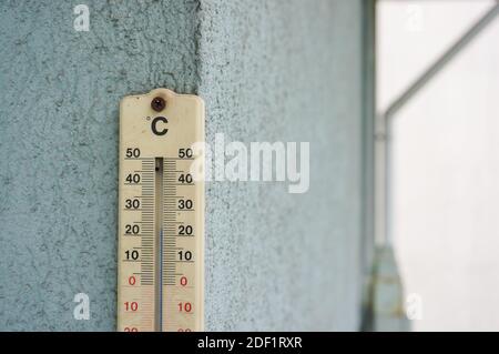 Eine Nahaufnahme eines Outdoor-Thermometers, das auf einem Beton hängt Wand Stockfoto