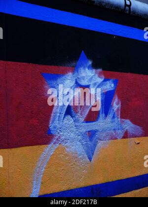 Aktenfoto vom 17. Oktober 2019 von der Berliner Mauer mit antisemitischen Graffiti, das Wandbild, das ursprünglich 1988 auf der East Side Gallery Wand als Erinnerung an den 40. Jahrestag des Kristallnacht-Pogroms in Nazi-Deutschland gemalt wurde, Zeigt eine israelische Flagge mit dem Davidstern auf einer deutschen Flagge. Der Künstler Günther Schaefer restaurierte das Außenkunstwerk zuletzt im März letzten Jahres. Es wurde Berichten zufolge im Laufe der Jahre mindestens 51 Mal verunreinigt. Die East Side Gallery besteht aus 105 Gemälden von Künstlern aus aller Welt, die 1990 auf der Ostseite der Berliner Mauer gemalt wurden. Berlin, Deutschland Stockfoto