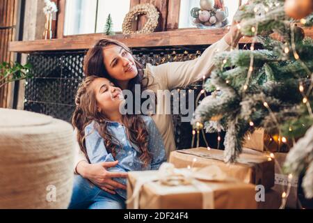 Mutter und Tochter bewundern Weihnachtsbaum zu Hause. Frohe Weihnachten und Frohes neues Jahr. Familie mit Spaß genießen Winterurlaub Feier Stockfoto