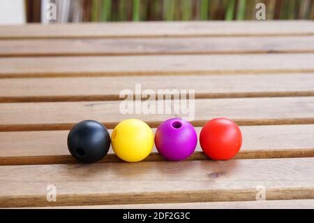Vier runde Objekte in den Farben Schwarz, Gelb, Lila und Rot Stockfoto