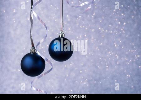 Zwei blaue weihnachtskugeln auf silbernem Bokeh Hintergrund. Minimale Zusammensetzung im Winter. Neujahrskonzept, Platz kopieren. Stockfoto