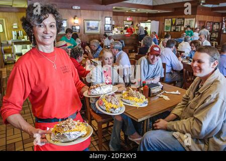 Alabama Decatur Big Bob Gibson BBQ Restaurant, innen Frau weibliche Kellnerin Serviererin, die Schweinefleisch Rindfleisch Huhn serviert, Bar-b-q gefüllte gebackene Kartoffeln, Stockfoto