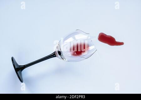 Gebrochenes Weinglas mit verschüttetem Rotwein auf weißem Hintergrund, Draufsicht Stockfoto