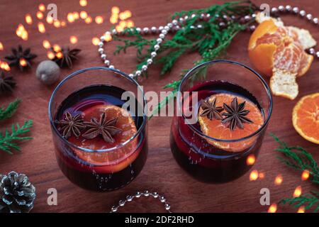 Zwei Gläser Glühwein mit Zitrusfrüchten, Sternanis, Muskatnuss auf Holztisch. Weihnachtliches Glühgetränk, Neujahrsdekoration, Draufsicht. Stockfoto