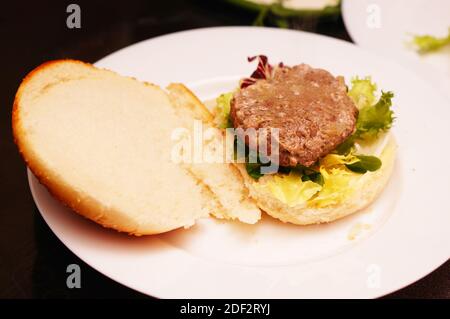 Das Brötchen des Burgers wartet darauf, angesetzt zu werden Das Patty Stockfoto