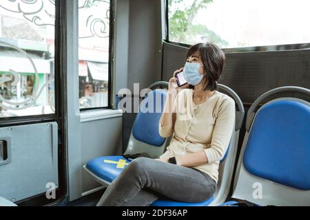 asiatische Frau Reiten ein öffentlicher Verkehr trägt Gesichtsmaske während Pandemie Stockfoto