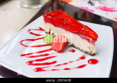 Eine Nahaufnahme eines Käsekuchen mit Gelee und bedeckt Dekoriert mit Erdbeere und roter Marmelade Stockfoto