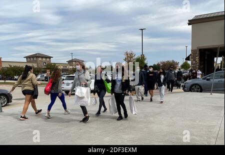 Allen, TX / USA - 27. November 2020: Nahaufnahme von Menschen, die die Maske tragen und die Einkaufstaschen tragen, die in den Allen Premium Outlets auf B spazieren gehen Stockfoto