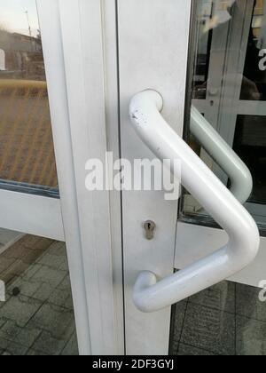 Vertikale Aufnahme des weißen Griffs einer Glastür Stockfoto