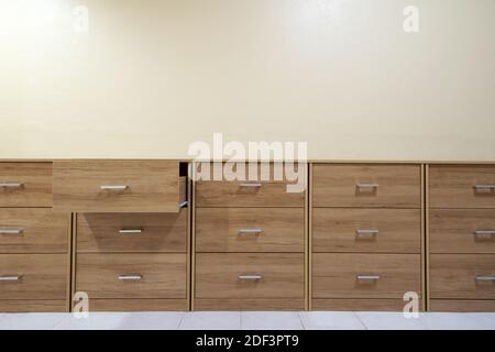 Kommode aus Holz mit offenen Schubladen vor einem Zementwand Hintergrund. Stockfoto