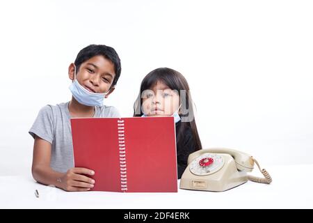 Ein Bruder und eine Schwester mit Schutzmaske studieren zusammen zu Hause, Homeschooling neue normale Konzept Stockfoto