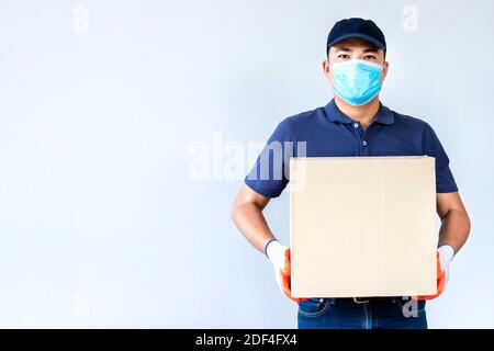 Asiatische Lieferung Mann Mitarbeiter in blauer Kappe blank T-Shirt Uniform Gesichtsmaske Handschuhe halten leere Karton-Box isoliert auf weißem Hintergrund , Konzept der prev Stockfoto