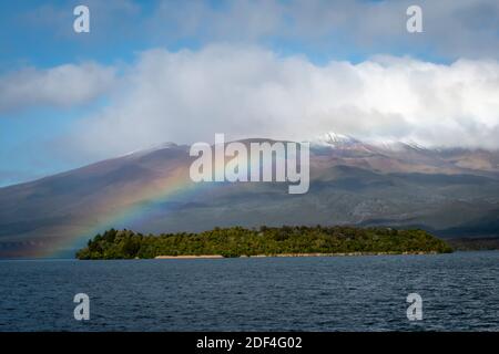 Regenbogen über dem See Rotoaira und Motuopuhi Island, mit Mount Tongariro in der Ferne, Tongariro National Park, North Island, Neuseeland Stockfoto