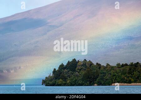 Regenbogen über dem See Rotoaira und Motuopuhi Island, mit Mount Tongariro in der Ferne, Tongariro National Park, North Island, Neuseeland Stockfoto