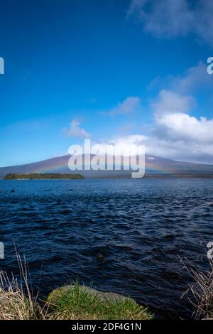 Regenbogen über dem See Rotoaira und Motuopuhi Island, mit Mount Tongariro in der Ferne, Tongariro National Park, North Island, Neuseeland Stockfoto