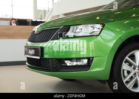 Die Vorderseite des neuen grünen Autos steht im Showroom eines Autohauses mit der Rezeption im Hintergrund. Stockfoto