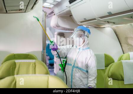 Fluglinienpersonal in Schutzkleidung (PSA) mit medizinischem Gesicht Desinfizierende Maske für Covid-19 oder Coronavirus in der Flugzeugkabine Nach oder vor Stockfoto