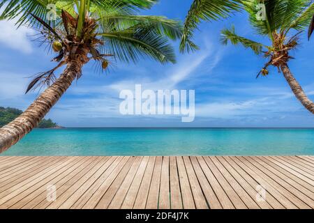 Tropischer Sonnenstrand mit Holzboden, Palmen und dem türkisfarbenen Meer auf Paradise Island. Stockfoto