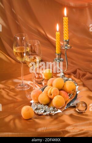 Zwei Gläser, Aprikosen und Kerzen auf der Fabric studio Hintergrund Stockfoto