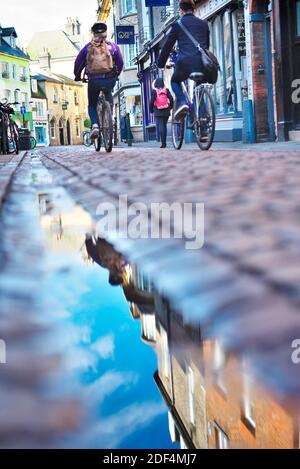 Kopfsteinpflasterstraßen in Cambridge, Großbritannien, mit Fahrradausleihschildern und Touristen und Einheimischen, die täglich auf dem Fahrrad unterwegs sind Stockfoto