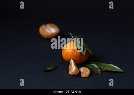 Frische Mandarinfrucht mit grünen Blättern isoliert auf einem schwarzen Hintergrund Stockfoto