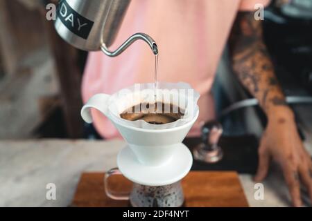 Tropfenden Kaffee, Barista gießt Wasser auf Kaffeepulver mit Filter, Brühen von Kaffee Stockfoto