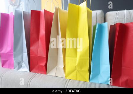 Viele bunte Papiertüten mit Einkäufen stehen auf dem Sofa Zu Hause Stockfoto
