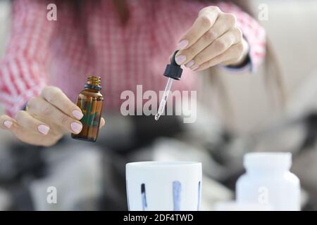 Weibliche Hände tropfende Marihuanaöl Tropfen von der Pipette in den Becher Nahaufnahme Stockfoto