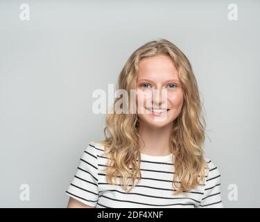 Schöne junge lächelnde blonde Frau ohne Make-up an der weißen Wand. Stockfoto