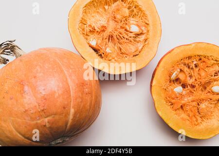 Minimalistisches Stillleben mit Kürbissen, ganz und halb auf hellem Hintergrund. Herbstkonzept mit Platz für Text Stockfoto