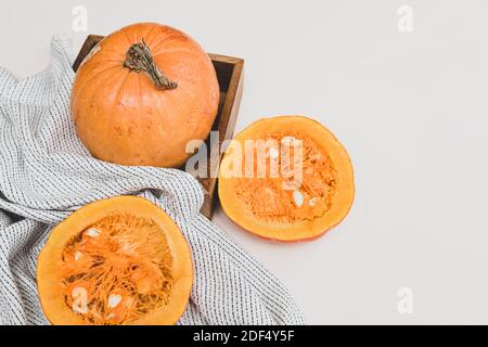 Minimalistisches Stillleben mit Kürbissen, ganz und halb auf hellem Hintergrund. Herbstkonzept mit Platz für Text Stockfoto