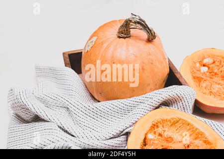 Minimalistisches Stillleben mit Kürbissen, ganz und halb auf hellem Hintergrund. Herbstkonzept mit Platz für Text Stockfoto