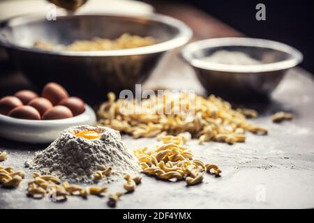 Zutaten für eine italienische Pasta mit Eigelb, Mehl und Schüsseln. Stockfoto