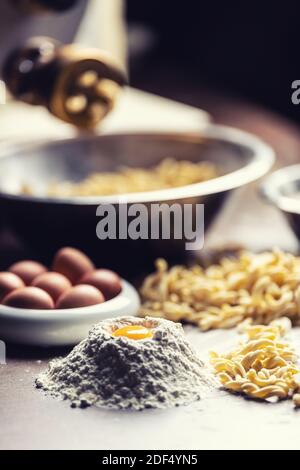 Eier, Mehl und frisch zubereitete Pasta aus der Pasta-Maschine auf dunklem Grund. Stockfoto