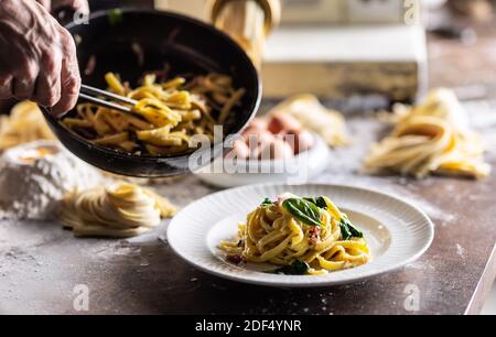 Italienische Ei-Spaghetti oder Fettuccine aus einer Pfanne von einem professionellen Koch überzogen. Stockfoto