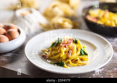 Eiernudelspaghetti mit Basilikum und Speck auf einem Teller. Stockfoto