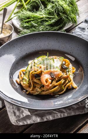 Linguine Pasta mit geräuchertem Lachs, Zucchini und frischem Fenchel auf einem dunklen Teller serviert. Stockfoto