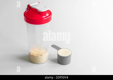 Vanillemolkenproteinlöffel. Sporternährung. Molkenproteinshaker auf weißen Hintergrunsen. Stockfoto