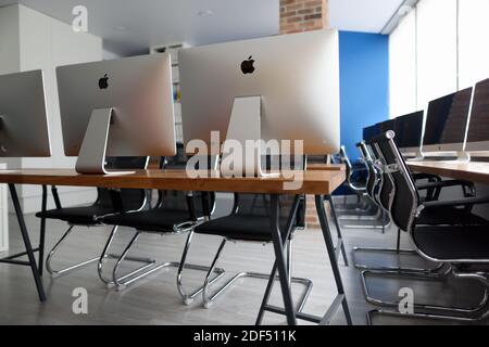 Minsk, Weißrussland - 30. Juli 2020: Viele silberne Monitore für Geschäftsleute stehen auf Holztisch in leerem Büro Nahaufnahme Stockfoto