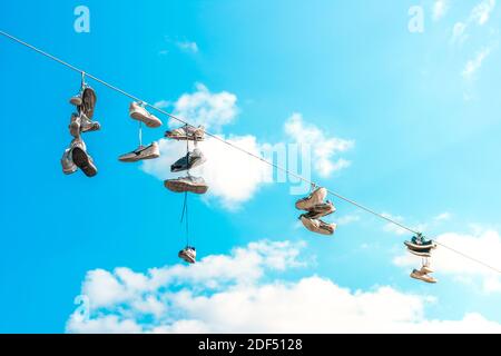 Schuhe werfen. Alte Sneaker auf Power Lines. Baumelnde Schuhe. Stockfoto