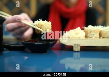 Person legt Sushi in Sojasauce im Restaurant Stockfoto