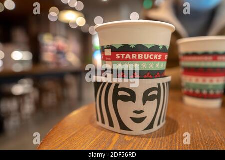 Eine Kaffeetasse aus Papier, die speziell für Weihnachten auf dem Tisch in einem Starbucks-Geschäft gemacht wurde. Stockfoto