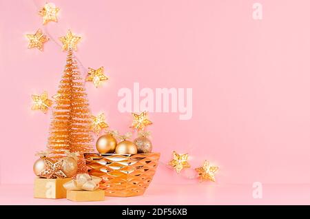 Weihnachtliche festliche Hintergrund mit goldenem Funkeln Dekoration in Schale, weihnachtsbaum, glühende Girlande auf rosa Hintergrund. Stockfoto