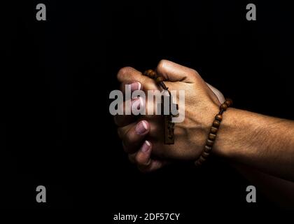 Die Hände der Frau halten einen hölzernen Rosenkranz und beten Stockfoto