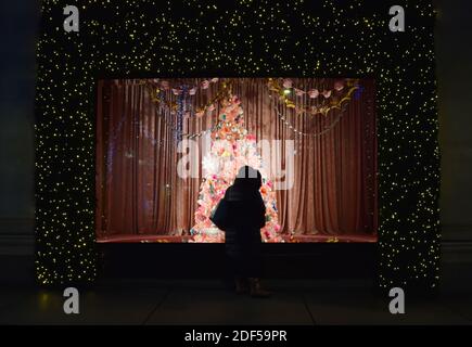 Eine Frau bewundert einen Weihnachtsbaum im Schaufenster des Selfridges-Geschäfts in der Oxford Street, London. Stockfoto