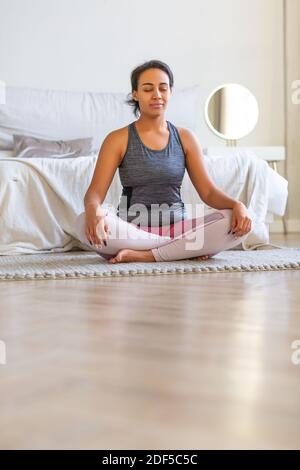 afroamerikanische Frau, die zu Hause Yoga praktiziert. Vertikales Foto. Stockfoto