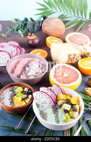 Frühstück grün Joghurt Schale gekrönt mit pitaya, Ananas, Chia Samen und Beeren mit palm leaf auf Stein Hintergrund, Stockfoto