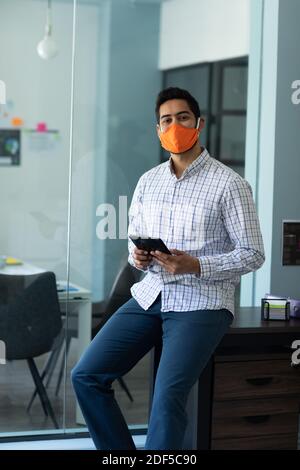 Gemischter Mann mit Gesichtsmaske in einem Büro Stockfoto